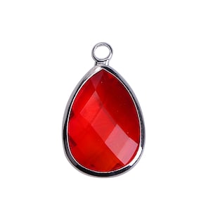 Peut inclure: Pendentif en forme de goutte d'eau, rouge et facetté, serti dans un cadre en métal argenté. Le pendentif comporte une petite boucle en haut pour l'attacher à une chaîne ou à un autre composant de bijouterie.