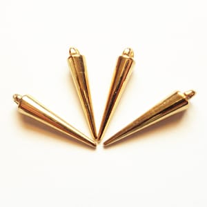 Könnte beinhalten: Vier goldfarbene, kegelförmige Anhänger aus Metall mit einer Öse oben.