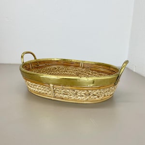 May include: Oval woven wicker basket with brass handles and a brass rim.