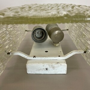 May include: White ceiling light fixture with two frosted glass shades. The shades have a textured, bubble-like pattern. The fixture has a white metal base and two metal arms.