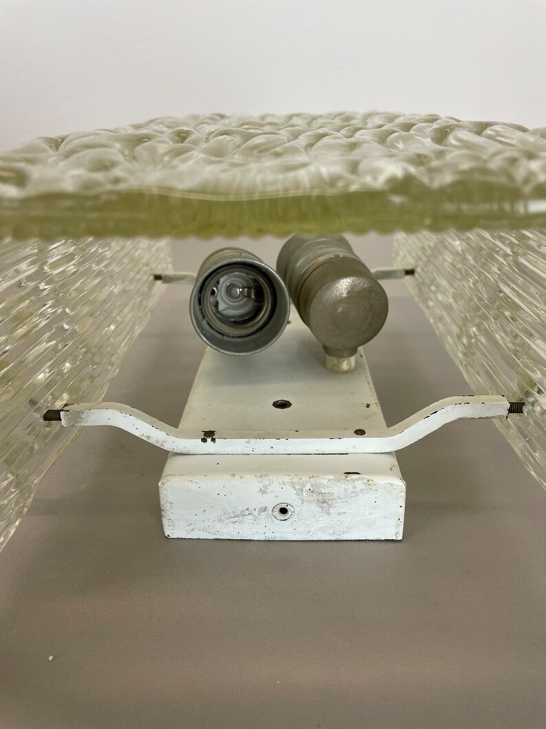May include: White ceiling light fixture with two frosted glass shades. The shades have a textured, bubble-like pattern. The fixture has a white metal base and two metal arms.