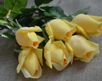 Pode incluir: Um buquê de seis rosas artificiais amarelas com caules e folhas verdes.