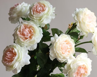 May include: A bouquet of artificial roses with white petals and pink centers. The roses are arranged in a cluster with green leaves.