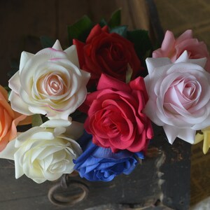 May include: A bouquet of artificial roses in various colors, including peach, white, pink, red, and blue. The roses are arranged in a wooden box.