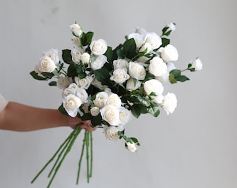 Peut inclure: Un bouquet de roses artificielles blanches avec des tiges et des feuilles vertes.