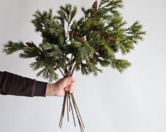 May include: A bunch of artificial pine sprigs with brown pine cones. The sprigs are green and have a natural look.