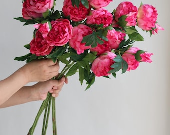 May include: A bouquet of pink artificial peonies with green stems and leaves.