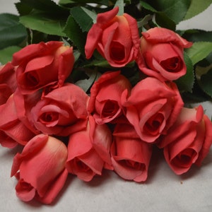 Puede incluir: Un ramo de rosas rojas artificiales con hojas verdes. Las rosas est&aacute;n dispuestas en un racimo, con los tallos apuntando hacia la parte inferior de la imagen.