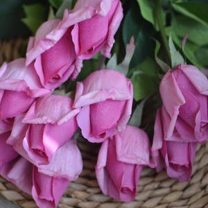 May include: A bouquet of pink roses with a light pink hue, arranged in a woven basket.