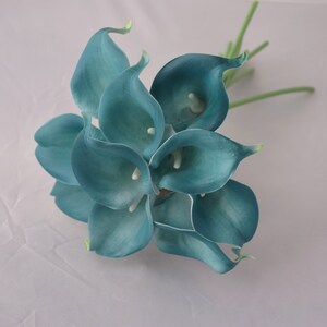 Op de afbeelding: Een boeket van teal kunstmatige calla lelies met groene stelen.