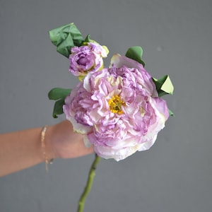 May include: A single pink and white artificial lotus flower with green leaves. The flower has a yellow center.