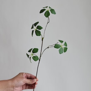 Puede incluir: Una sola rama artificial con cuatro hojas verdes, que mide 43 cm de largo. El texto "This is one branch-17" es visible en la imagen.