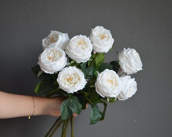 Pode incluir: Um buquê de rosas artificiais brancas com folhas verdes. As rosas têm uma cor branca cremosa e uma aparência ligeiramente enrugada.
