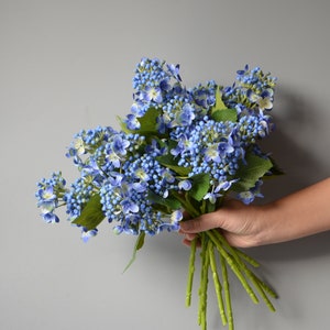 May include: A bouquet of blue artificial hydrangea flowers with green stems.