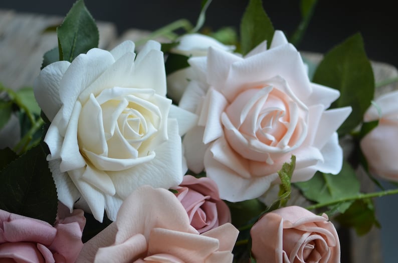 Op de afbeelding: Een boeket kunstmatige rozen in tinten wit, roze en blush. De rozen zijn in een cluster gerangschikt, met de witte rozen in het midden en de roze rozen eromheen.