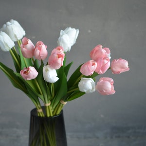May include: A bouquet of pink and white artificial tulips in a gray vase. The tulips are arranged in a vase on a gray background.