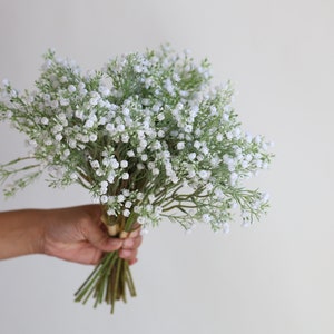 Op de afbeelding: Een boeket witte baby's breath bloemen met groene stelen.