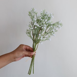 Op de afbeelding: Een boeket witte baby's breath bloemen gebonden met touw.