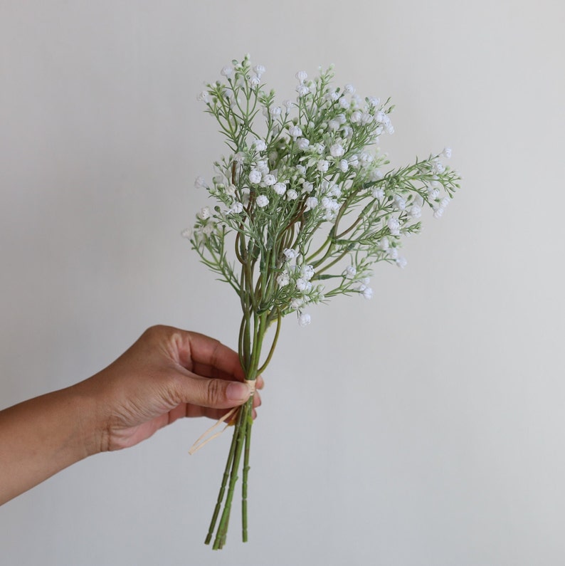 Op de afbeelding: Een boeket witte baby's breath bloemen gebonden met touw.