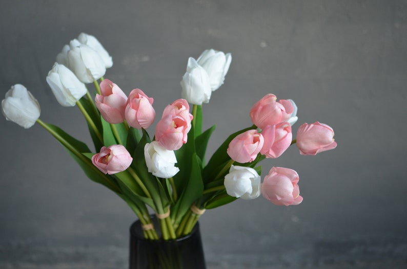 May include: A bouquet of pink and white tulips in a clear glass vase. The tulips are arranged in a loose, natural style.
