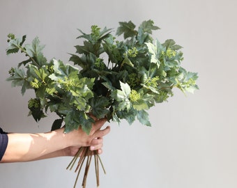 Op de afbeelding: Een bos kunstmatige groene druivenbladeren met kleine groene knoppen.