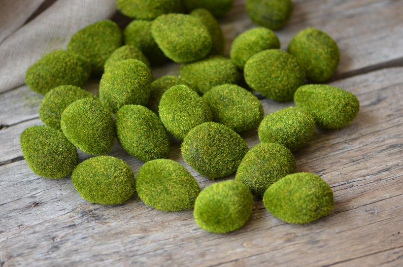 May include: A collection of moss-covered stones in various sizes and shapes. The stones are a vibrant green colour and have a soft, fuzzy texture.