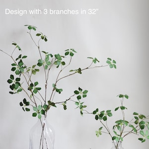 Puede incluir: Dos arreglos de vegetaci&oacute;n artificial en jarrones de vidrio transparente. El arreglo m&aacute;s grande tiene tres ramas y mide 81 cm de alto. El arreglo m&aacute;s peque&ntilde;o tiene cuatro ramas y mide 43 cm de alto. "Design with 3 branches in 32" y "Design with 4 branches in 17" est&aacute;n escritos debajo de los arreglos.