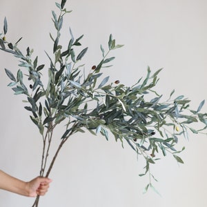 May include: A bunch of artificial olive branches with green leaves and small brown olives.