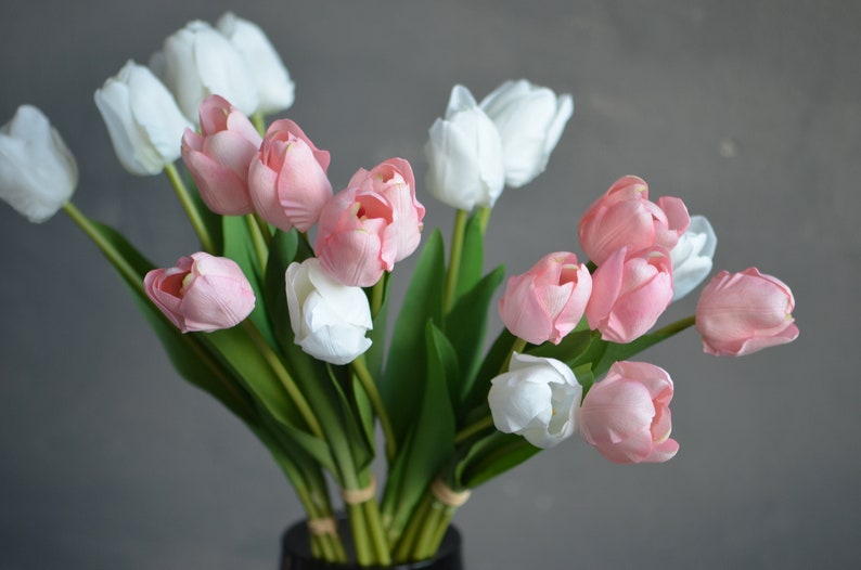 May include: A bouquet of pink and white artificial tulips with green stems and leaves.