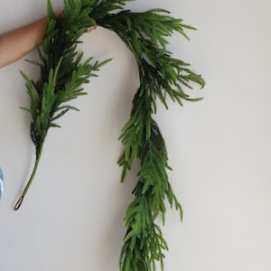 May include: A long, green artificial garland made of pine needles. The garland is flexible and can be shaped into a variety of designs.