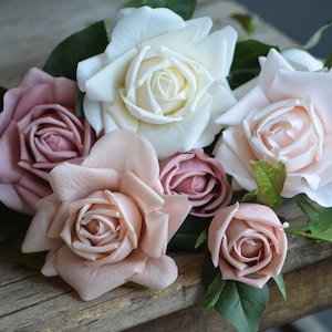 Op de afbeelding: Een boeket kunstmatige rozen in roze en witte tinten. De rozen zijn gerangschikt op een houten oppervlak.