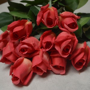 Puede incluir: Un ramo de rosas de seda rojas con hojas verdes. Las rosas est&aacute;n dispuestas en un racimo, con los tallos apuntando hacia arriba.