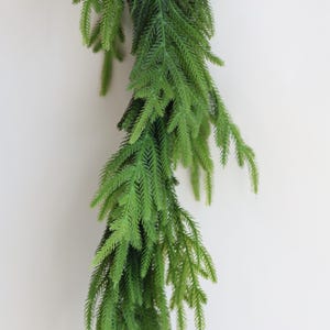 May include: A long, green garland of artificial pine branches, ideal for adding a touch of greenery to your home decor.