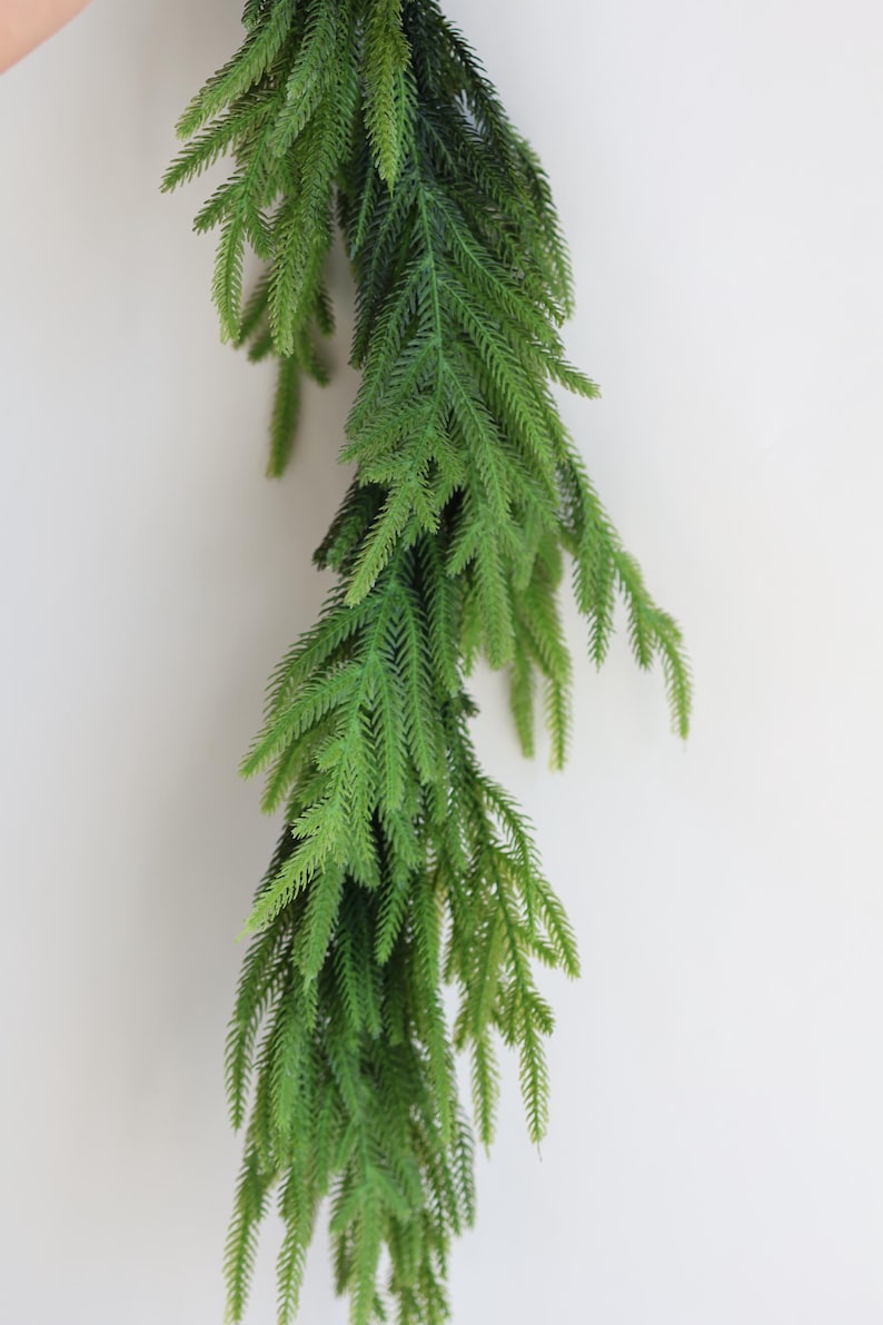 May include: A long, green garland of artificial pine branches, ideal for adding a touch of greenery to your home decor.