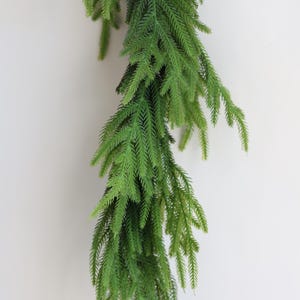 May include: A long, green garland of artificial pine branches, ideal for adding a touch of greenery to your home decor.