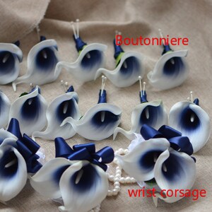 May include: A set of 12 white and navy blue calla lily boutonnieres with navy blue ribbon accents. The boutonnieres are arranged on a beige fabric background. The text "Boutonniere" is written in red on the top of the image. The text "wrist corsage" is written in red on the bottom of the image.