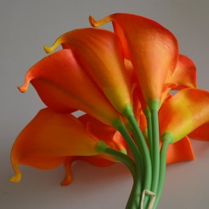 May include: A bouquet of orange calla lilies with green stems.