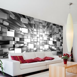 May include: A white couch with red pillows in front of a wall mural featuring a 3D design of silver and white cubes.