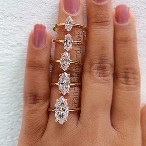 Peut inclure: Un ensemble de sept bagues en or avec des diamants de forme marquise de tailles différentes. Les bagues sont présentées sur une main, mettant en valeur les différentes tailles des diamants.