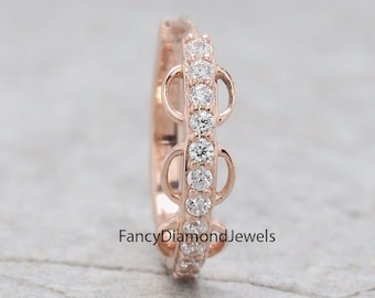Può includere: Un anello in oro rosa con un design delicato che presenta tre piccoli cerchi incastonati con pietre rotonde trasparenti. L'anello è incrostato con pietre rotonde trasparenti più piccole attorno a tutta la fascia.