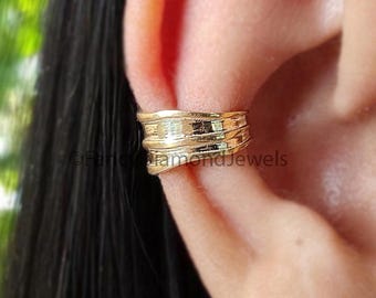 Könnte beinhalten: Goldener Ohrring mit einem strukturierten Design. Der Ohrring wird am oberen Teil des Ohrs getragen.