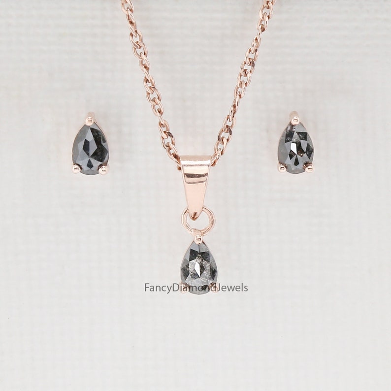 Puede incluir: Un conjunto de pendientes y un collar con colgante de diamante negro en forma de pera. Las joyas est&aacute;n engastadas en oro rosa y presentan una cadena delicada.