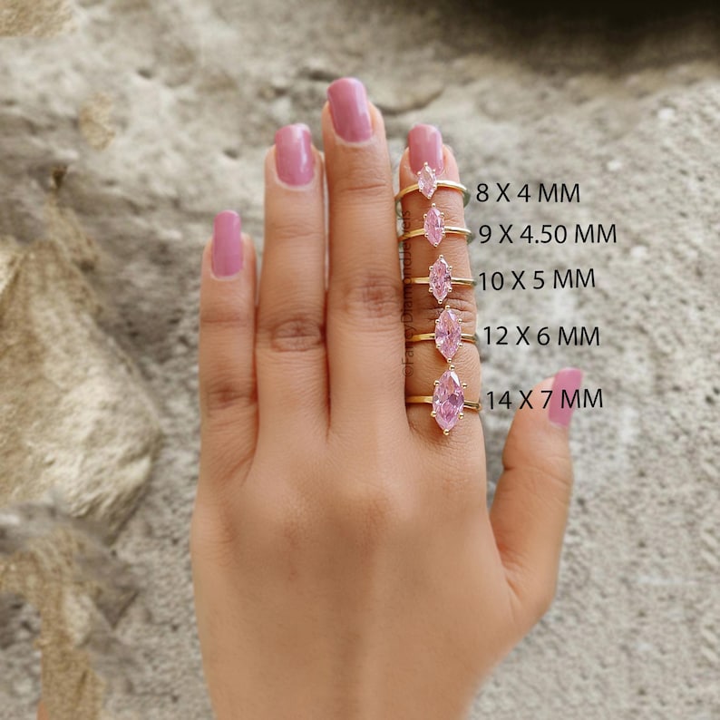Puede incluir: Cinco anillos de oro con piedras preciosas de forma marquesa rosadas de diferentes tama&ntilde;os. Los anillos se muestran en una mano, con el anillo m&aacute;s grande en la parte inferior y el anillo m&aacute;s peque&ntilde;o en la parte superior. Los tama&ntilde;os de los anillos se enumeran debajo de cada anillo: 8 x 4 mm, 9 x 4,50 mm, 10 x 5 mm, 12 x 6 mm, 14 x 7 mm.