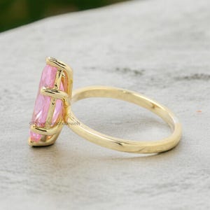 Puede incluir: Un anillo de oro con una gran piedra preciosa rosa en forma de marquesa. El anillo est&aacute; engastado en un estilo simple y elegante.