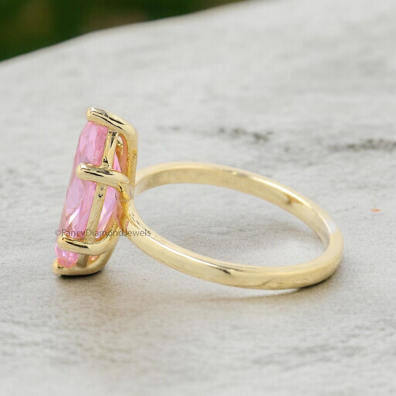 Puede incluir: Un anillo de oro con una gran piedra preciosa rosa en forma de marquesa. El anillo est&aacute; engastado en un estilo simple y elegante.
