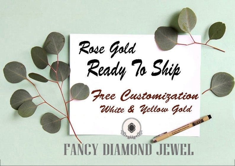 Puede incluir: Una tarjeta blanca con el texto "Rose Gold Ready To Ship Free Customization White & Yellow Gold" y el logotipo "FANCY DIAMOND JEWEL". La tarjeta est&aacute; sobre un fondo verde claro con hojas de eucalipto.