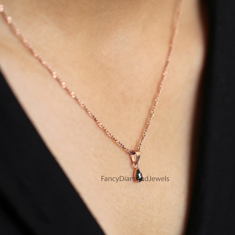 Puede incluir: Un delicado collar de cadena de oro rosa con un peque&ntilde;o colgante de diamante negro en forma de pera. El colgante est&aacute; engastado en un sencillo engaste de garras. El collar es una pieza de joyer&iacute;a cl&aacute;sica y elegante.