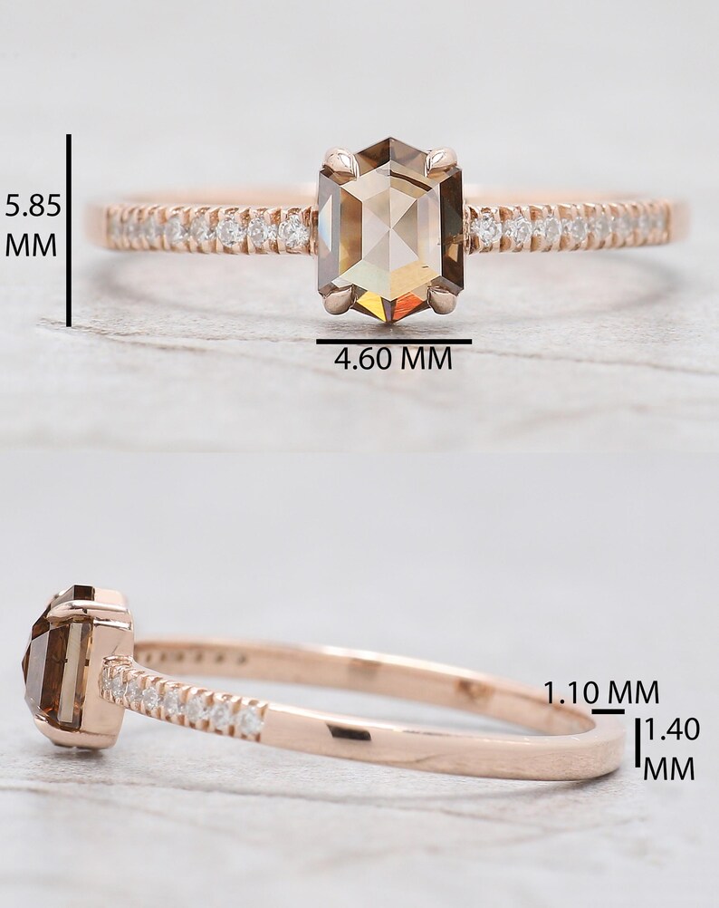 Op de afbeelding: Ros&eacute;gouden ring met een zeshoekige, lichtbruine edelsteen, met een afmeting van 5,85 mm x 4,60 mm. De band is bezet met kleine, heldere stenen. De ringband is 1,10 mm tot 1,40 mm dik. Close-up die het ontwerp en de details benadrukt.