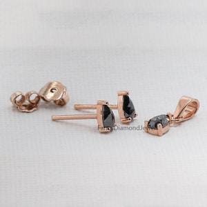 Puede incluir: Un juego de pendientes de diamantes negros y un colgante en oro rosa. Los pendientes son de bot&oacute;n con un diamante negro de forma de pera. El colgante es un diamante negro de forma de pera en una cadena de oro rosa.