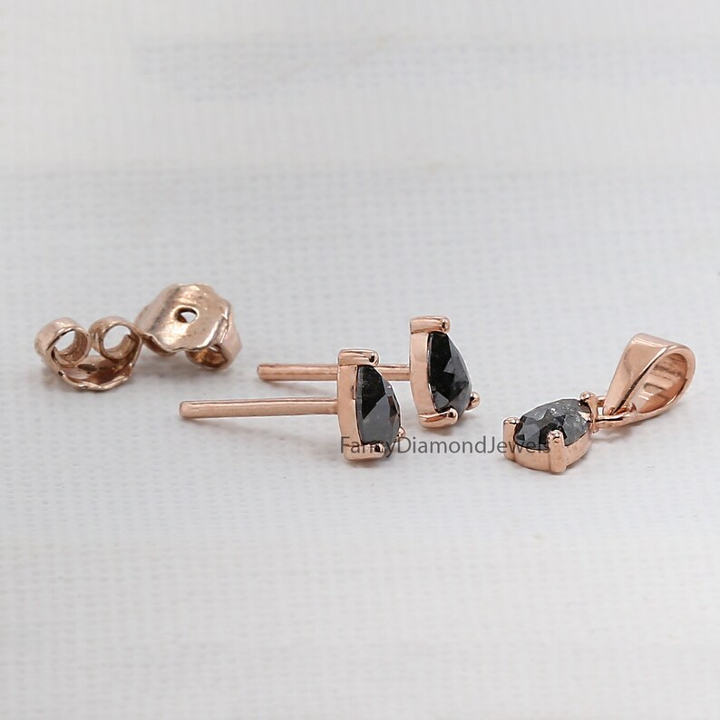 Puede incluir: Un juego de pendientes de diamantes negros y un colgante en oro rosa. Los pendientes son de bot&oacute;n con un diamante negro de forma de pera. El colgante es un diamante negro de forma de pera en una cadena de oro rosa.